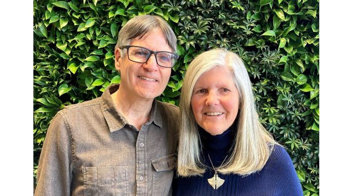 close-up photo of Peter and Nancy Torpey, hosts of Eyes On Success, standing in front of a wall of greenery