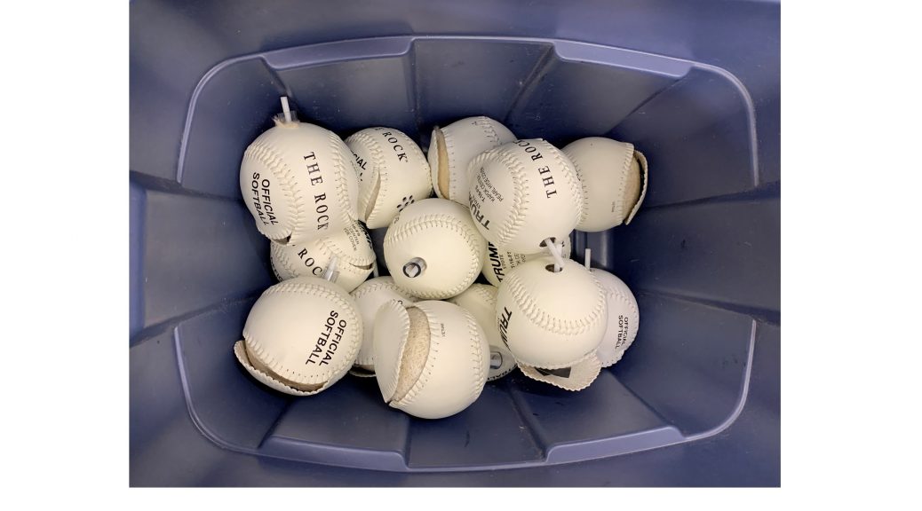 blue bin filled with partially completed white beep baseballs